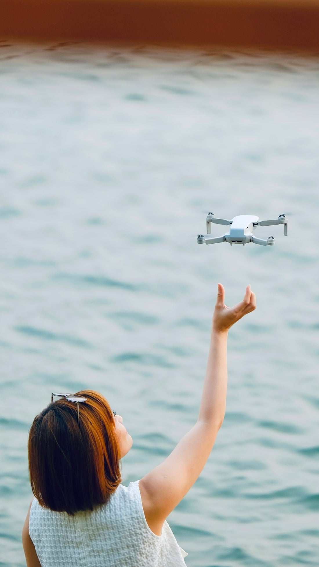 A woman flying a remote controlled airplane over a body of water