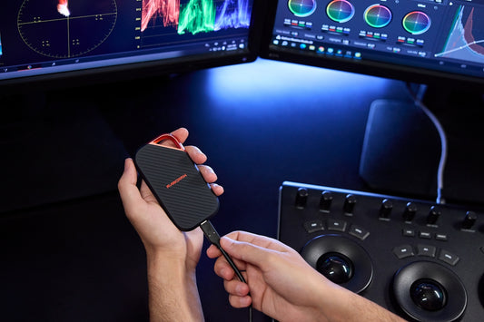 Person connecting a portable ssd to a video editing setup.
